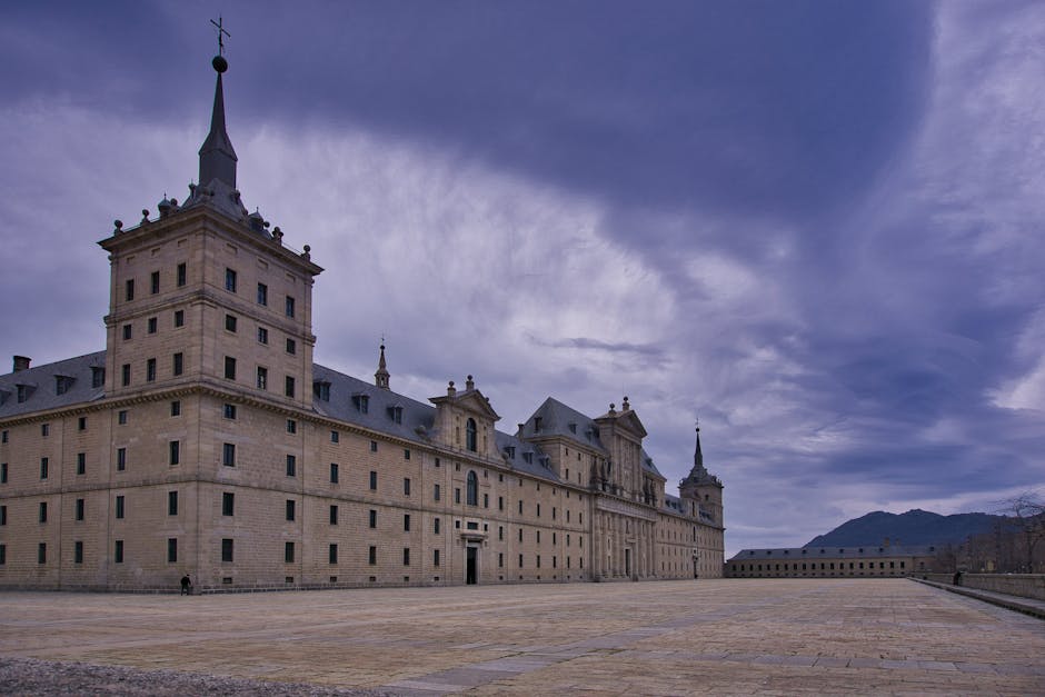 Explore the majestic El Escorial Monastery in Spain, framed by a vivid sky. Perfect for history and architecture enthusiasts.