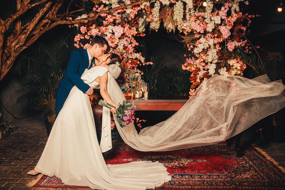 Newlywed couple kissing under a beautiful floral arch. Capturing an elegant wedding moment.